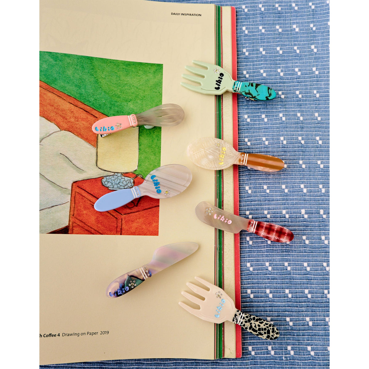 Likio kitchen utensil hair clips laid on a blue tablecloth beside a plate