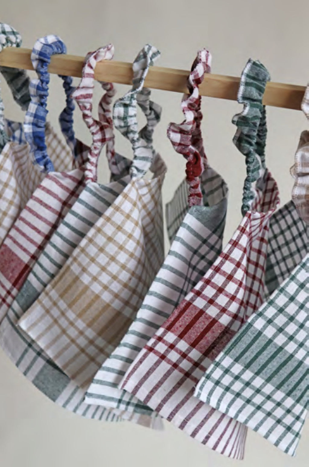 Rij kinderslabbetjes in torchon van Ensemble hangend aan een houten stang